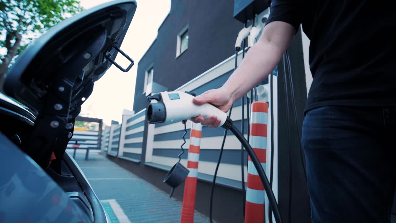 전기 자동차의 연료 충전 과정: 전기 에코 자동차가 충전하는 치 아래의. 전기 자동차 충전 치는 자동으로 열립니다. 남성 손이 발기 된 자동차를 입합니다.