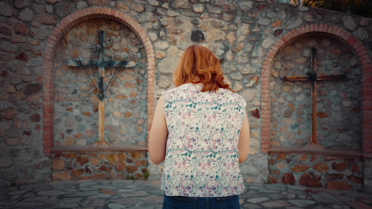 Mulher reza em crucifixo religioso ao ar livre para acabar com as guerras no mundo