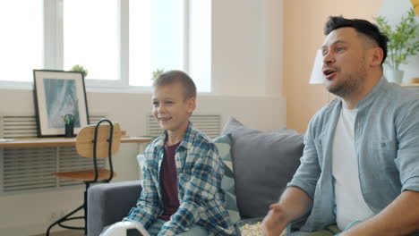 father and son watching a soccer game at home