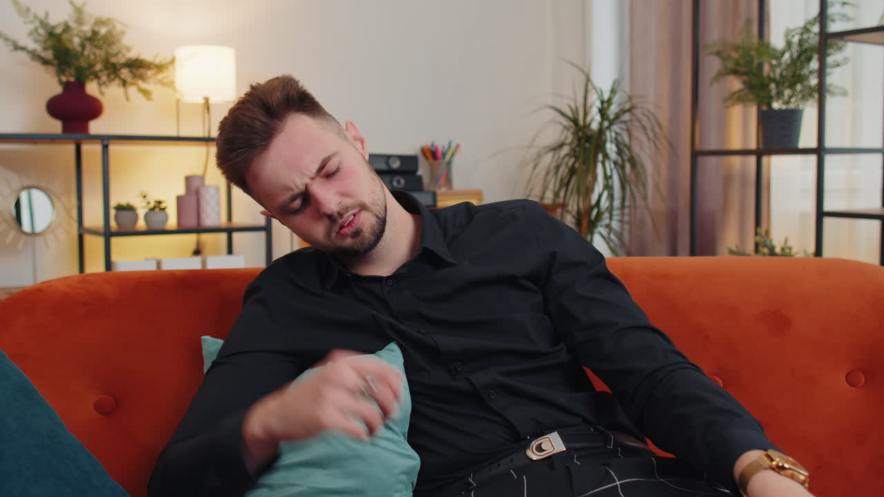 Giovane uomo a casa che soffre per una situazione ingiusta, una rottura, depresso, si sente male, esaurito.