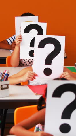 school kids covering their face with question mark sign