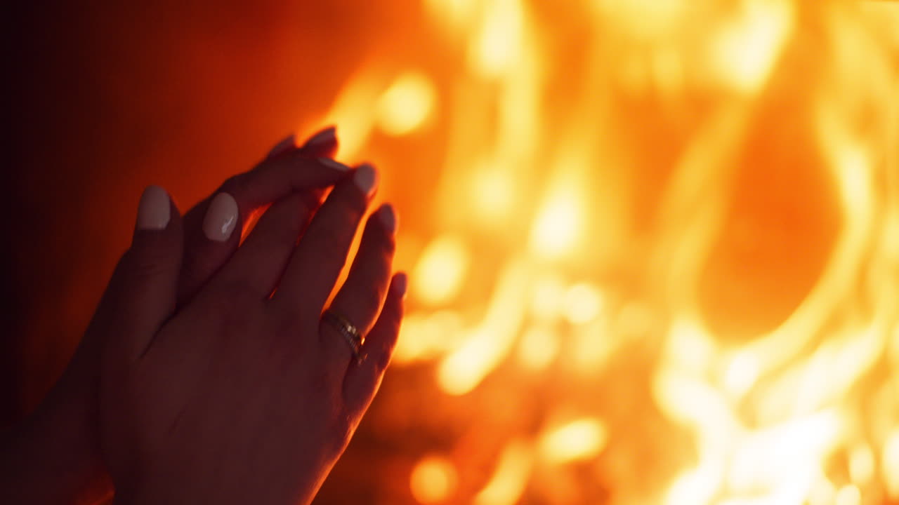 여자는 집에 있는 벽난로 옆에서 손을 따뜻하게 한다