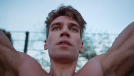 Closeup-focused-sportsman-doing-pull-ups-in-playground.-Guy-practicing-workout