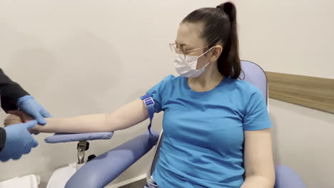 capture of a nurse putting on a tourniquet and adjusting a woman patient for her blood test