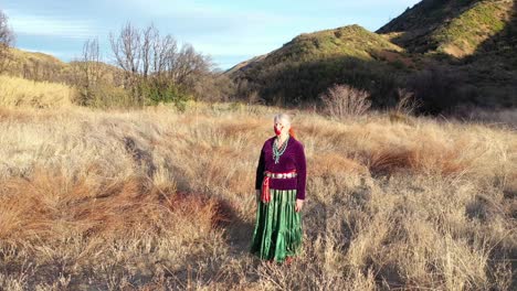 Excelente-Toma-Aérea-De-Una-Mujer-Navajo-Parada-En-Un-Campo-En-Ojai,-California