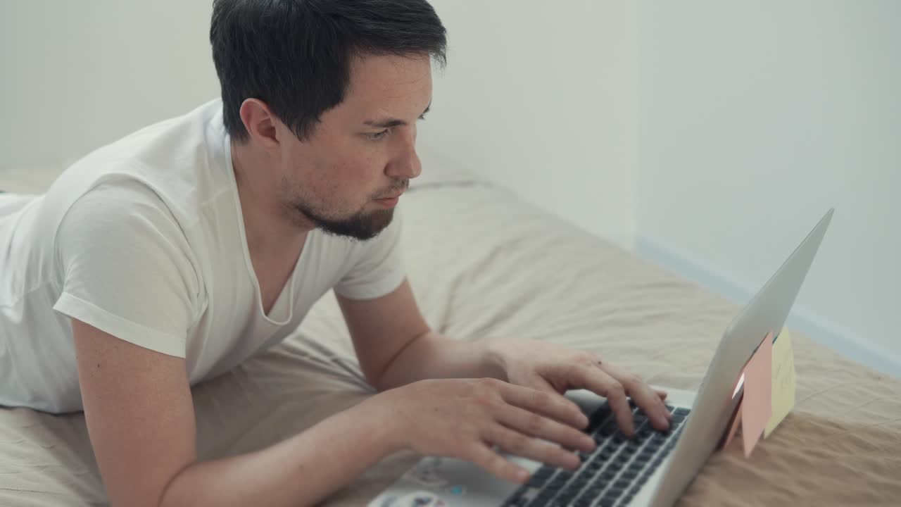 hombre trabajando en una computadora portátil en una cama en casa