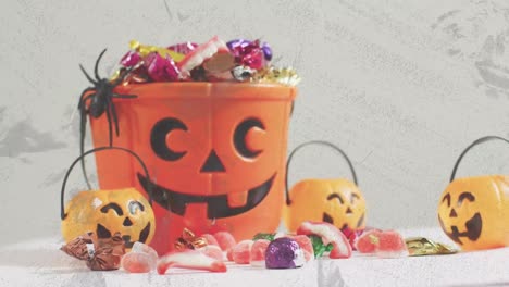 animation of halloween carved pumpkin buckets with sweets on grey background