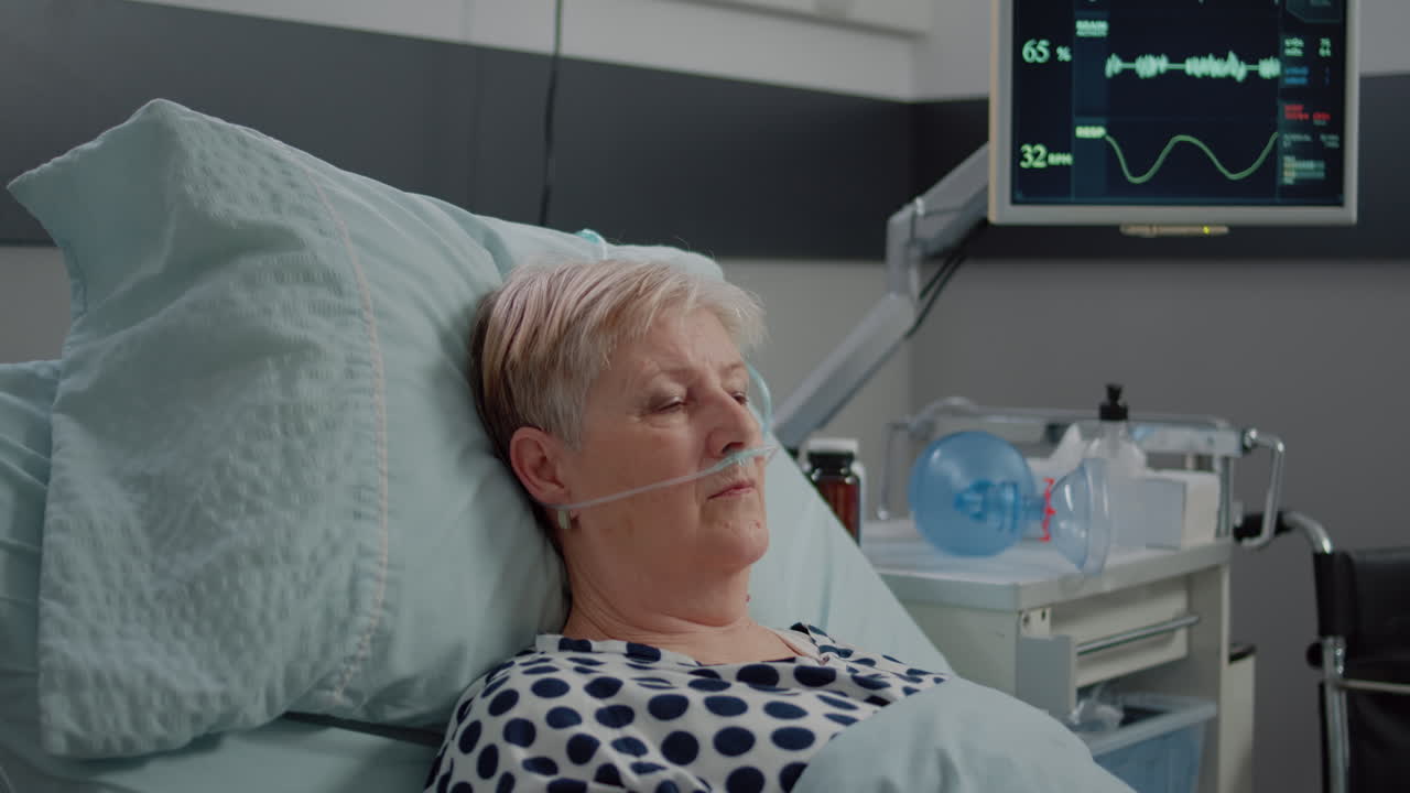 Portrait of elder patient with oxygen tube laying in hospital ward bed