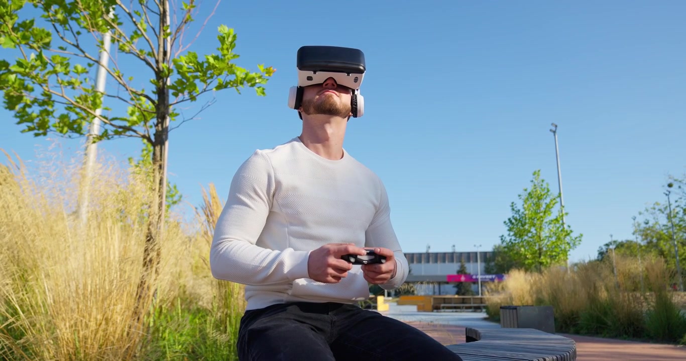 Giovane uomo che gioca a un gioco di realtà virtuale all'aperto con un controller