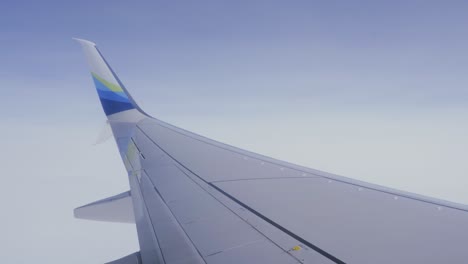 passenger pov airplane wing flying through blue skies flight