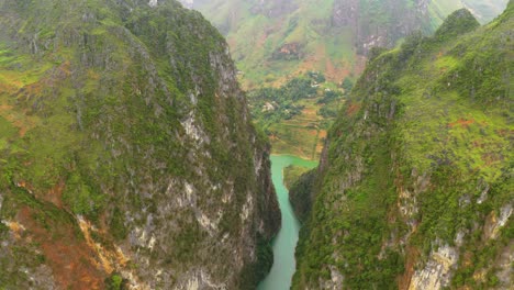 Aerial-dolly-backwards-through-steep-canyon-walls-over-the-gorgeous-turquoise-blue-green-water-of-the-Nho-Que-river-in-northern-Vietnam