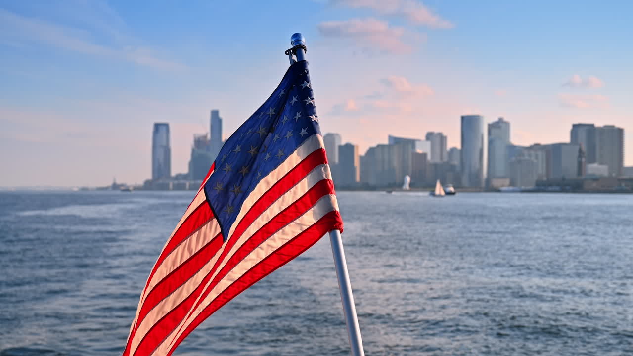 Bandiera americana che sventola sul retro della barca che naviga lungo il fiume. Skyline sfocato di New York sullo sfondo