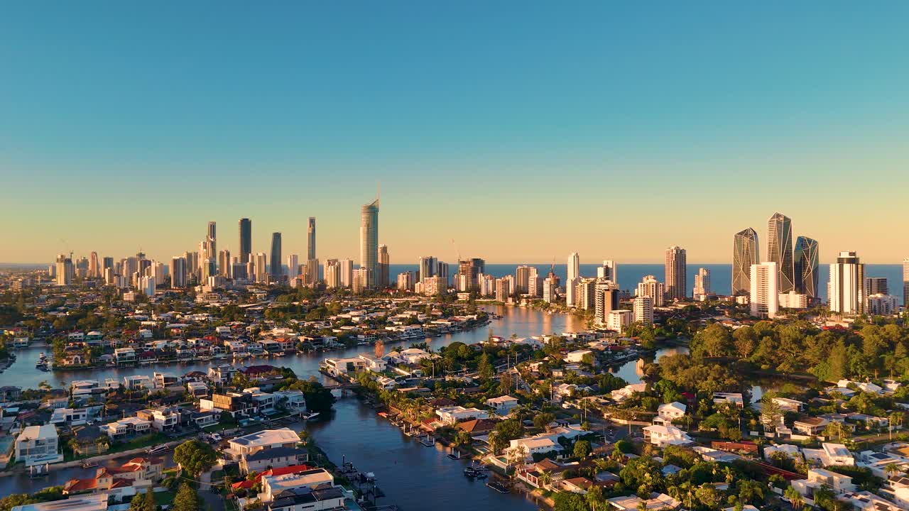 Drone captures dynamic Gold Coast skyline with vibrant sunset hues, showcasing urban landscape and waterways in a 14-second hyperlapse