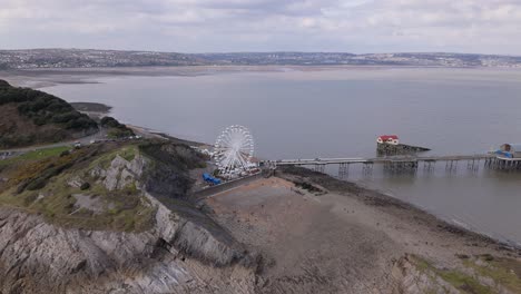 aerial tracking right above mumbles pier in swansea, uk, with the big wheel standing against the cloudy sky