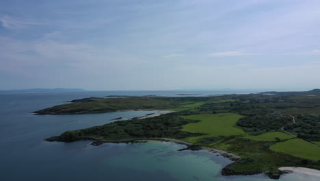 aerial shot of the coastal waters and land around the island of islay, showing a bus sky and bright blue water