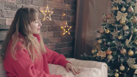chica guapa posa en el sofá cerca del árbol de navidad decorado
