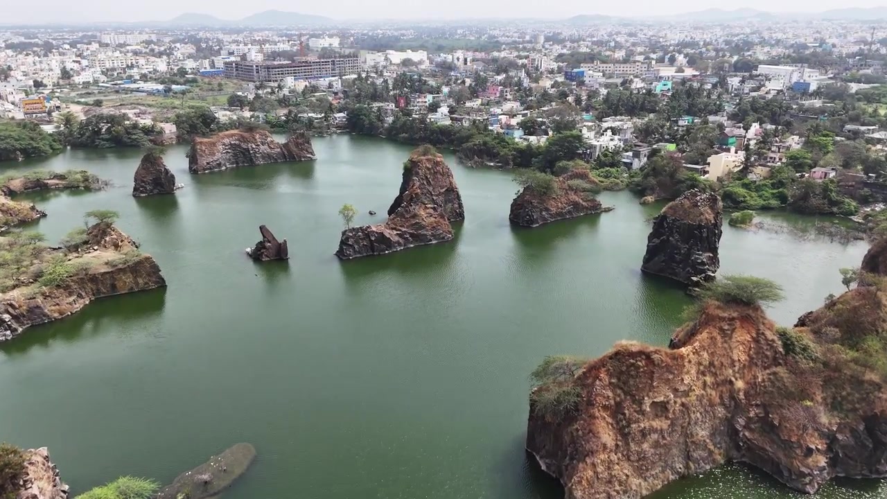 Vista aerea della Cava di granito di Sikkarayapuram, che mostra imponenti formazioni rocciose di granito che emergono da laghi di cava color smeraldo. Pozzi di scavo allagati, scogliere frastagliate e lo skyline distante di Chennai.