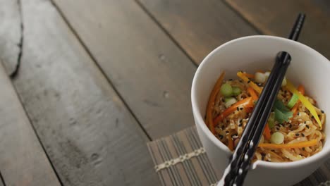 Composition-of-bowl-of-pad-thai-with-chopsticks-on-wooden-background