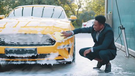 hombre lavando un coche amarillo en un lavado de coches de autoservicio