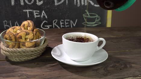 a cup of tea and homemade cookies on a cafe table.tea is pouring from a transparent teapot.menu.4k