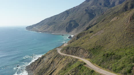 Vista-Aérea-De-La-Autopista-De-La-Costa-Pacífica-En-La-Costa-De-California-Con-Montañas-Y-Océano