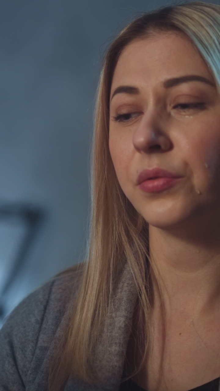 una mujer rubia triste llora mirando la foto de rayos x de un niño con una enfermedad incurable sentada en una oficina semicolor en un hospital por la noche.