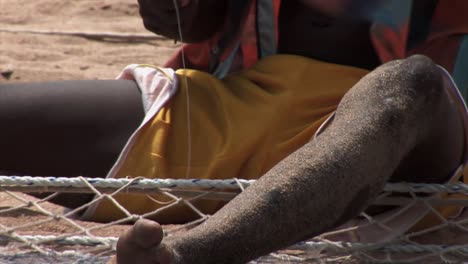 las manos del pescador nigeriano reparando la red