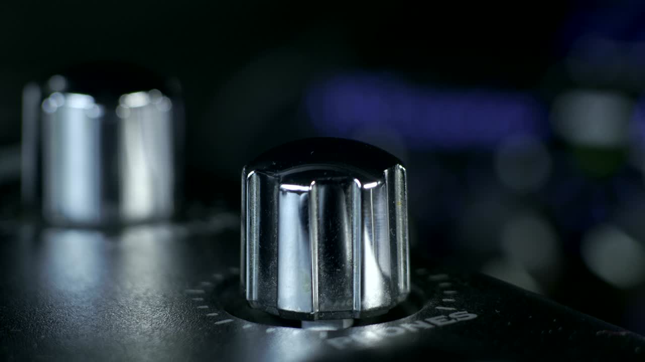 los dedos masculinos girando el botón de la interfaz de audio plateado