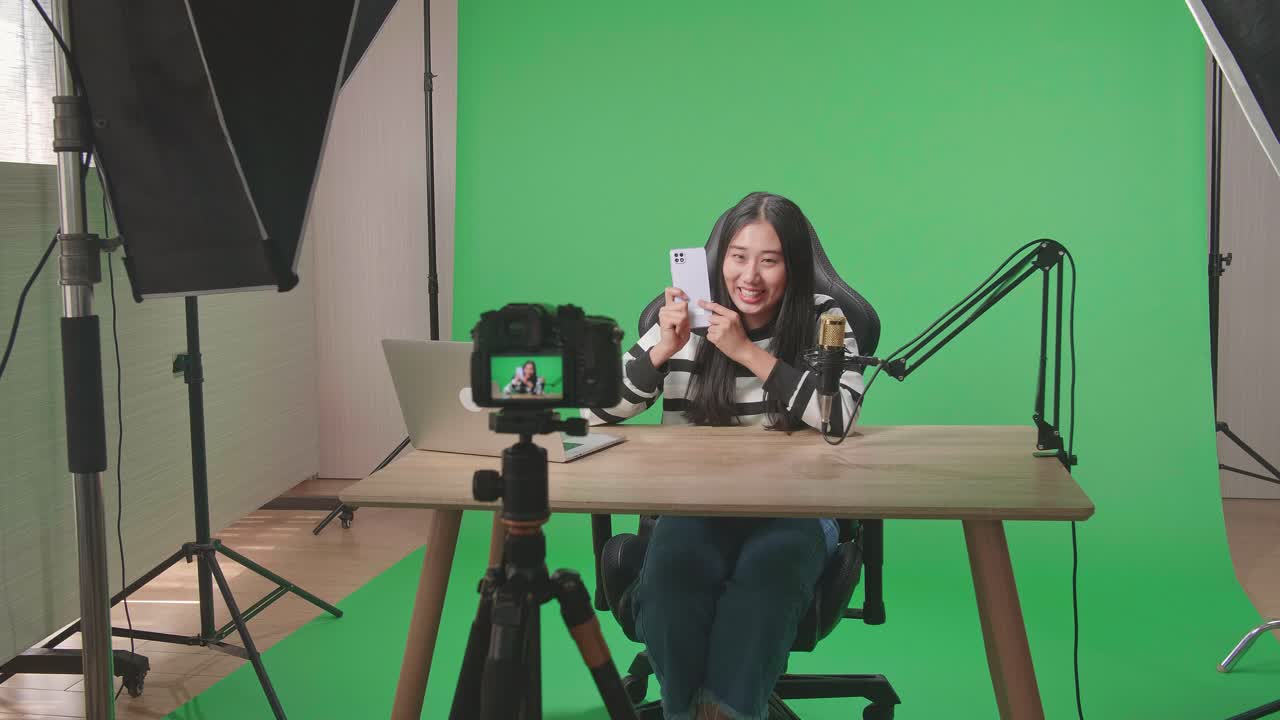 Vlogger donna che registra un video in uno studio con green screen e smartphone.