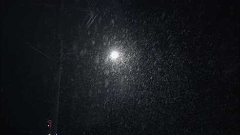 Winter-snowfall-at-night-snowing-on-city-street-in-street-light