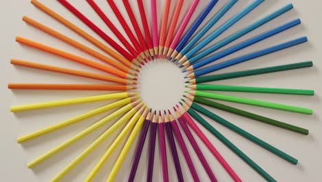 Video-of-central-composition-with-colorful-crayons-on-white-surface