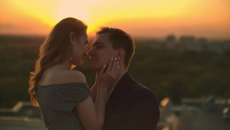 gli amanti si guardano negli occhi sul tetto al tramonto. una coppia romantica sul tetto.