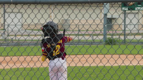 a slow-motion shot captures a little league baseball player at bat dodging an inside pitch, while the catcher stands up and throws the ball, showcasing the action and teamwork in the game.