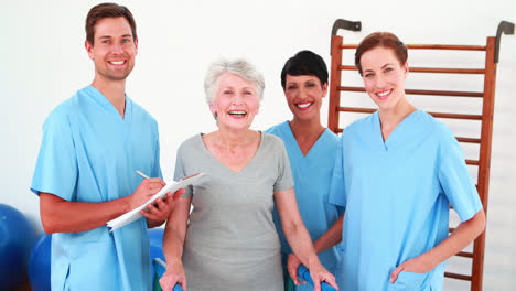 elderly woman smiling and talking with her physical rehab team