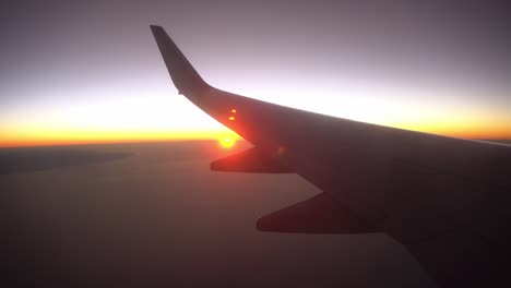 amanecer desde el avión de portillo, vista del ala desde la ventana del avión, plano de silueta al amanecer del sol