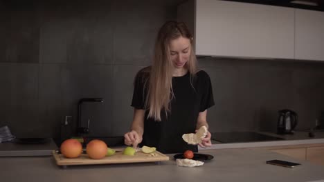 Woman-cleans-pomelo-slice-in-the-kitchen-on-a-counter