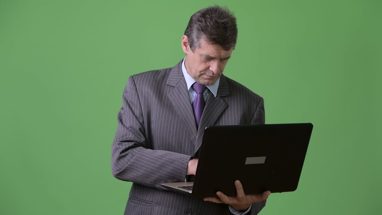 hombre de negocios maduro y guapo contra un fondo verde