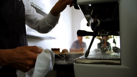 camarero limpiando una máquina de espresso en el mostrador