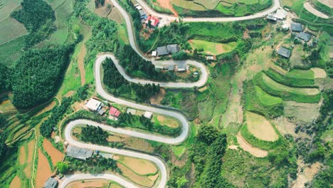 Crazy-switchback-hairpin-road-zig-zagging-and-weaving-meandering-through-green-patchwork-hillside-of-northern-Vietnam