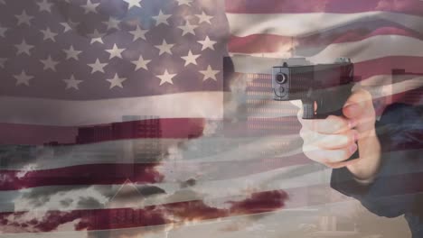 animation of hand holding pistol over waving american flag, modern buildings and cloudy sky