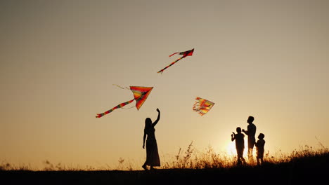 un joven sam con dos niños juega cometas al atardecer en un lugar pintoresco actividad familiar al aire libre