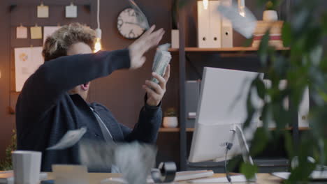 man celebrating success in office with money