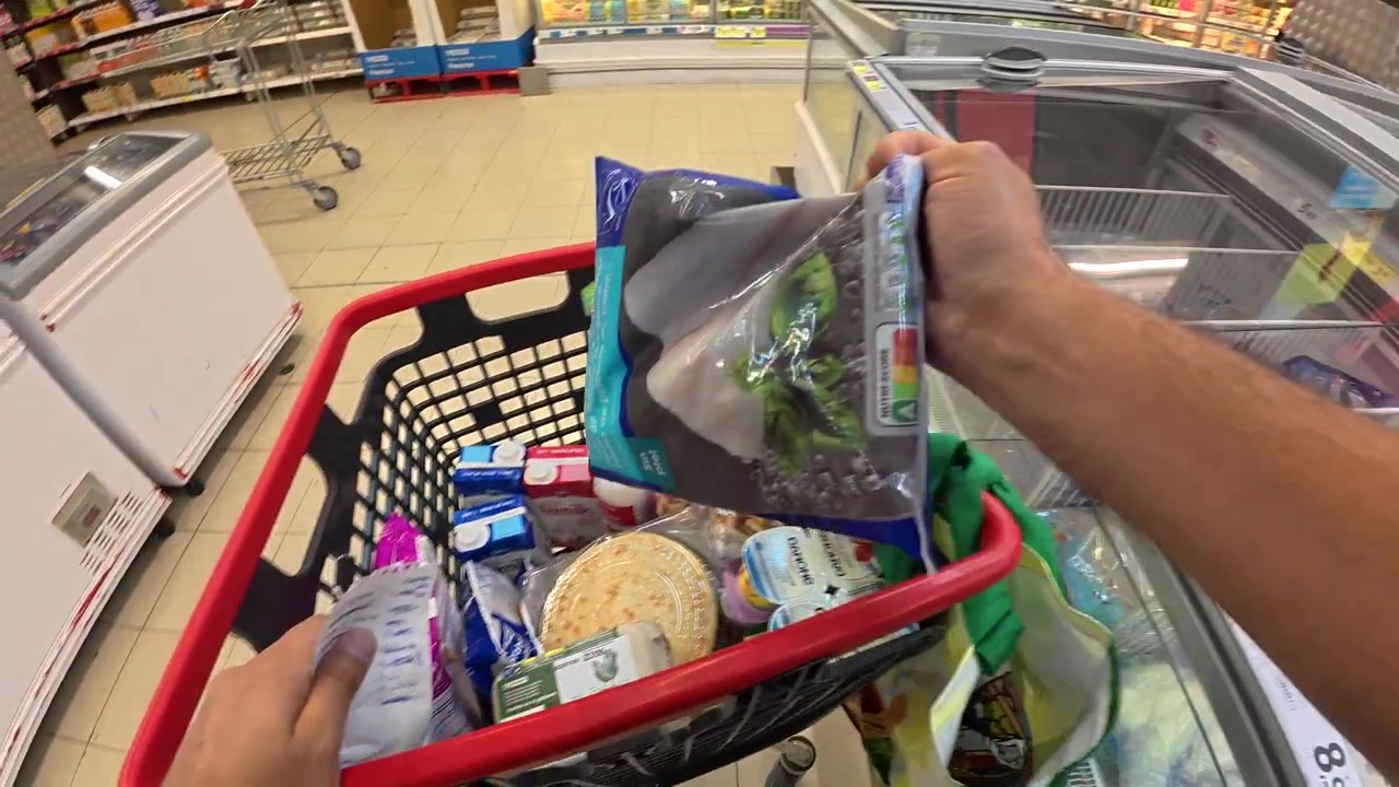 Vista en primera persona de compras de alimentos congelados en un supermercado.