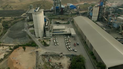 capturing of a cement factory by drone with loaders and trucks parked outside in pakistan.