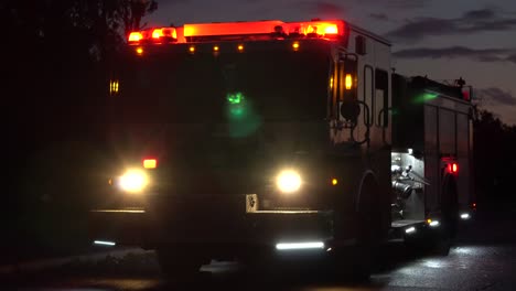 close-up shot of the front left hand side of a huge firetruck in the evening with its lights on and reflections on the ground after a huge tornado tore apart the town outside of ottawa