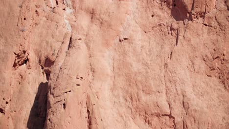 climbers ascending the sheer red rocks at garden of the gods, under a clear sky