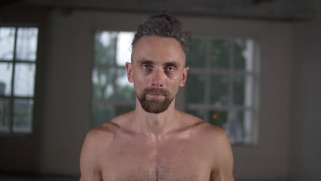retrato en primer plano de un hombre caucásico guapo sin camisa con rastas elegantes mirando a la cámara con motivación de pie en el pasillo vacío en el interior