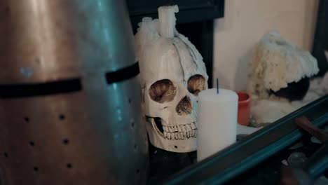 medieval helmet beside a skull shaped candle, evoking a gothic and mysterious ambiance