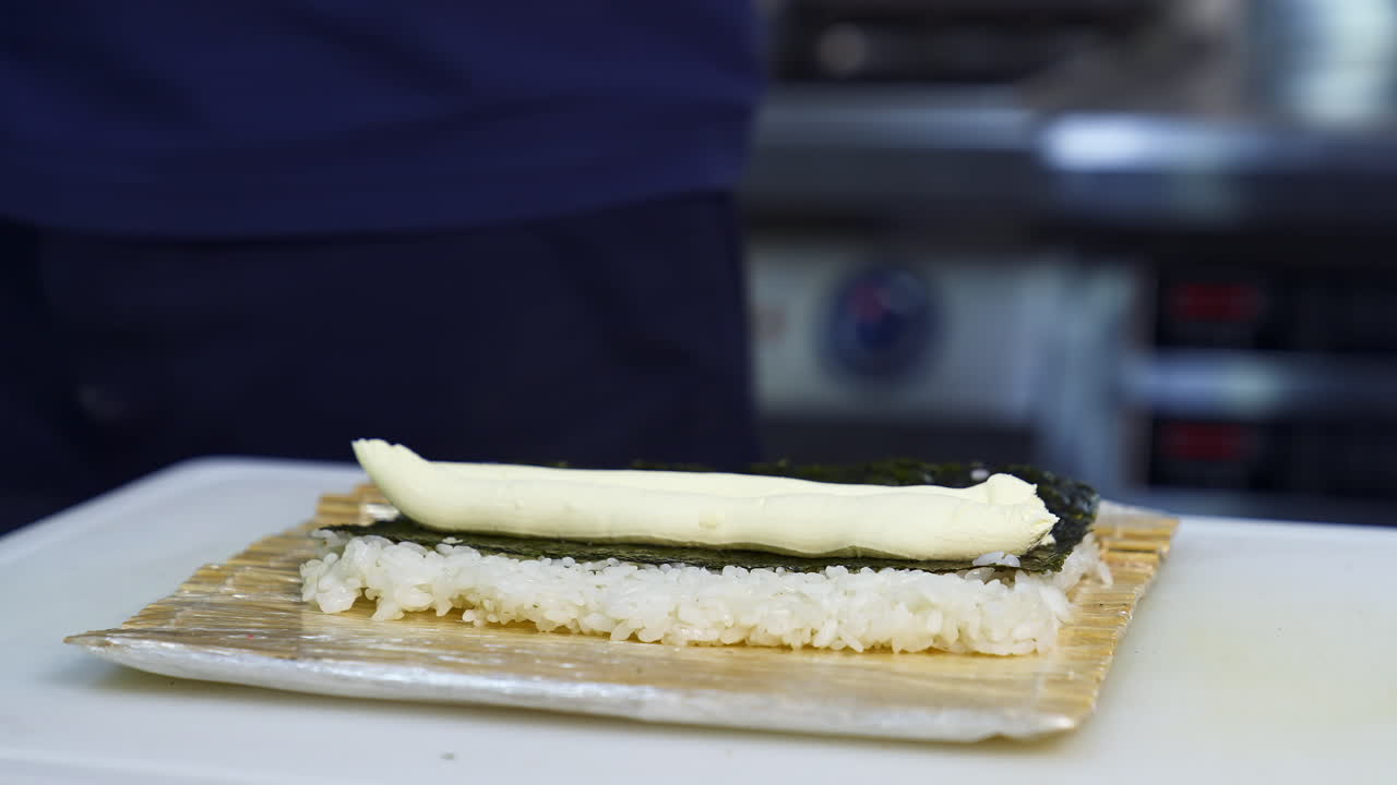 Chef puts cream cheese on sushi. The process of sushi cooking, preparing. Japanese cuisine concept. Process of complex dish.