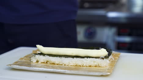 chef puts cream cheese on sushi. the process of sushi cooking, preparing. japanese cuisine concept. process of complex dish.